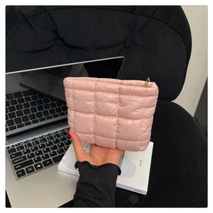 Nahaufnahme einer rosa gesteppten Kosmetiktasche mit goldenem Reißverschluss in der Hand