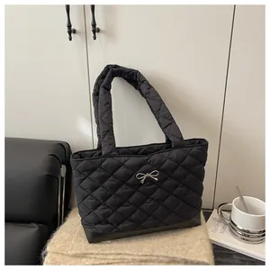 Detail of black quilted tote bag featuring a silver bow and glossy rhombus pattern