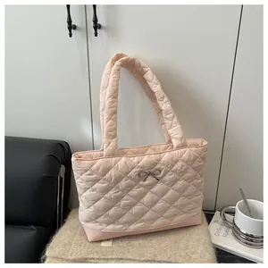 Detail of light pink quilted tote bag featuring diamond stitching and silver bow charm