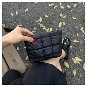 Nahaufnahme der schwarzen gesteppten Puffer-Clutch aus Nylon in herbstlicher Außenumgebung