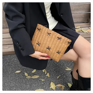 Braune gesteppte Clutch mit schwarzen Schleifen-Stickereien, präsentiert von einem Model