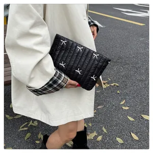 Details einer schwarzen gesteppten Clutch mit weißen Schleifen-Stickereien für den Herbst