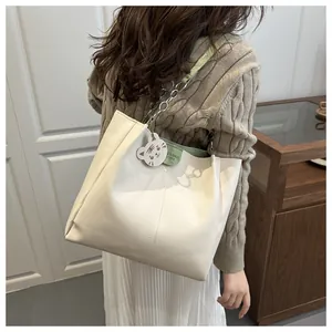 Detail of off-white tote bag with chain strap and cute cat charm for daily commute