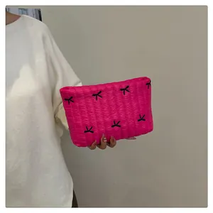 Detail der pinkfarbenen gesteppten Clutch mit schwarzen Schleifenstickereien bei einem Model
