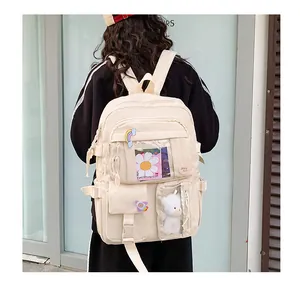 Dettaglio dello zaino in nylon beige crema con tasche multiple e portachiavi a orsetto