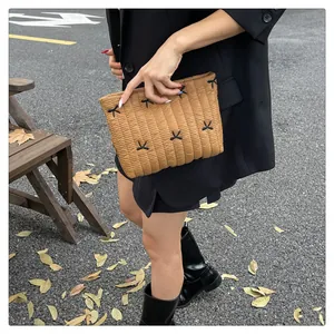 Straßenansicht einer gesteppten braunen Clutch mit schwarzen Schleifen und Plisseefalten