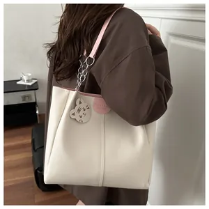 Detail of cream tote bag with pink straps and a cute tiger charm for daily commute