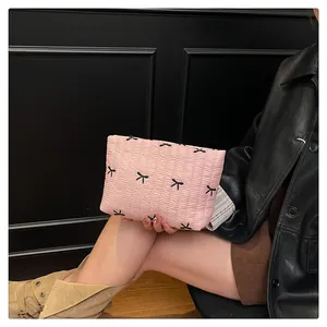 Nahaufnahme der rosa gesteppten Clutch mit schwarzen Schleifenstickereien und Glanzstoff