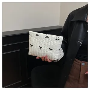 Detail der weißen Stepp-Clutch mit schwarzen Bogenschleifen-Stickereien und Polsterung