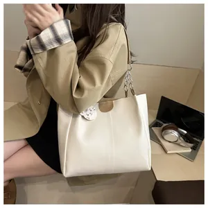 Close-up of white leather tote bag with silver chain strap and cute cat charm accessory