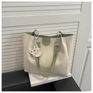 Detail of minimalist tote bag with green lining, silver chain and cat pendant charm