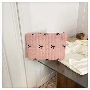 Detail der rosa gesteppten Kosmetiktasche mit schwarzen Schleifenstickereien auf Glanzstoff