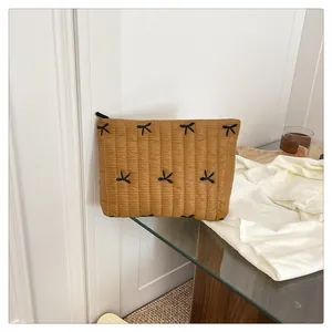 Nahaufnahme der senfgelben Stepptasche mit schwarzen Schleifenstickereien und Reißverschluss