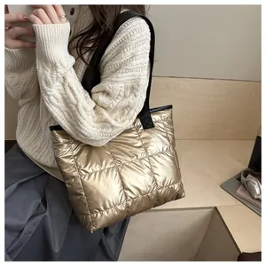 Detail of golden quilted tote bag with metallic finish and black nylon shoulder straps