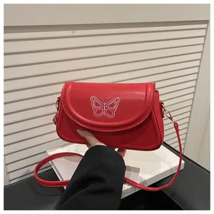 Detailansicht der roten Umhängetasche mit feiner weißer Schmetterlingsstickerei und Goldclip