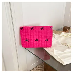 Nahaufnahme der rosaroten gesteppten Clutch mit schwarzen Schleifen und Stickerei