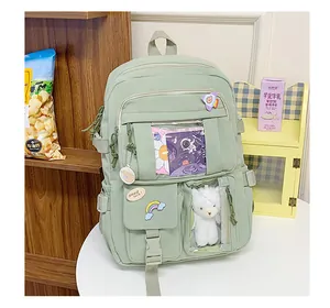 Dettaglio dello zaino verde chiaro con badge carini, tasche trasparenti e ciondolo morbido