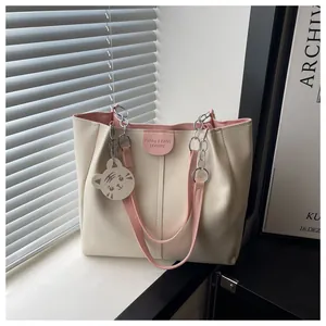 Detail of beige tote bag with pink straps and a cute cartoon tiger head charm