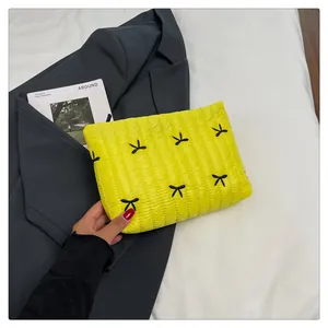 Detail einer leuchtend gelben gesteppten Kosmetiktasche mit schwarzen Schleifen-Stickereien