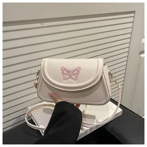 Detailansicht der rosa Schmetterlingsstickerei auf der cremefarbenen Kunstledertasche