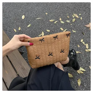 Detailansicht der braunen gesteppten Handtasche mit Stickerei vor herbstlichem Hintergrund