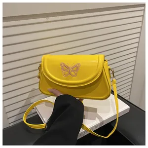 Detail der gelben Ledertasche mit feiner rosa Schmetterlingsstickerei auf der Taschenklappe