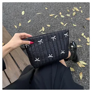 Detail einer schwarzen gesteppten Nylon-Handtasche mit weißen Schleifen auf einer Bank