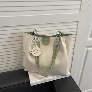 Minimalist cream and green tote bag with metal chain handles and a cute tiger charm