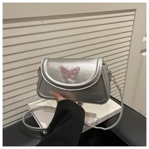 Detail der silbernen Metallic-Umhängetasche mit rosa Schmetterlingsstickerei und Klappe