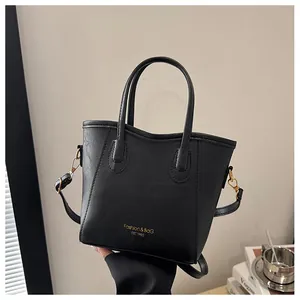 Detail of black leather bucket bag with gold lettering and adjustable shoulder strap