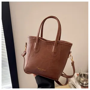 Detail of vintage brown lychee pattern leather handbag with gold logo and shoulder strap
