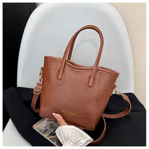 Detail of brown pebbled leather texture on bucket bag with gold lettering and hardware
