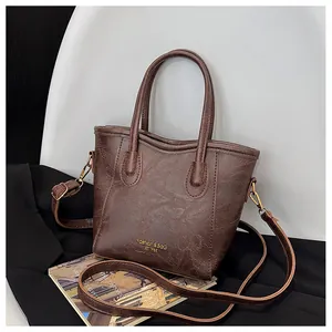 Detail view of the vintage brown pleated texture and gold logo on the crossbody bag