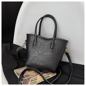 Close-up of black pleated faux leather handbag with gold hardware and logo detail
