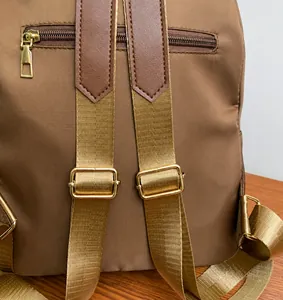 Detail of adjustable golden shoulder straps and nylon material on a brown casual backpack