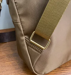 Close-up of golden square buckle on brown nylon backpack with fine textured fabric