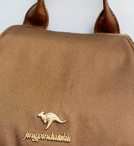 Close-up of brown textured fabric with gold kangaroo emblem and brand logo plate