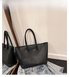 Detailed view of black matte leather tote bag with flap closure and slim handles