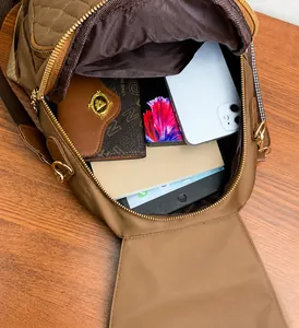 Spacious interior of brown quilted nylon bag showing storage for phone and tablet