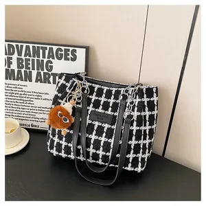 Detail of black and white plaid tweed tote bag with chain strap and plush pendant