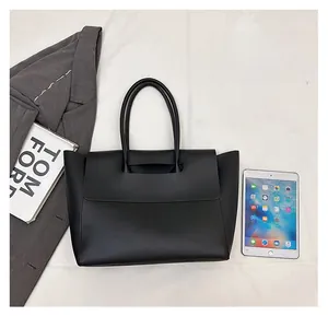 Black tote bag size comparison with iPad and books showing large storage capacity
