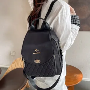 Detail view of a black quilted nylon backpack with a golden kangaroo logo and metal lock