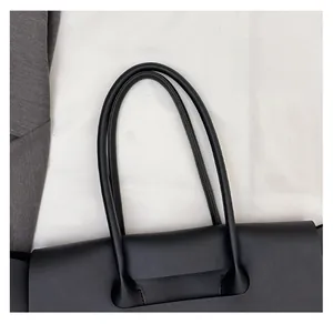 Close-up of rounded leather handles and stitching on a black commuter tote bag