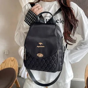 Detail view of black quilted backpack with golden kangaroo logo and turn-lock closure