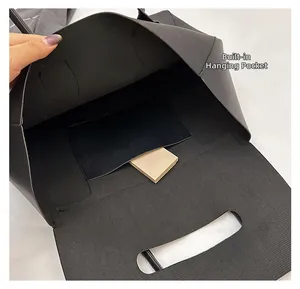Detail view of the internal hanging pocket and fine texture inside a black tote bag