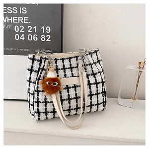 Detail of black and white tweed tote bag with leather handles and plush charm