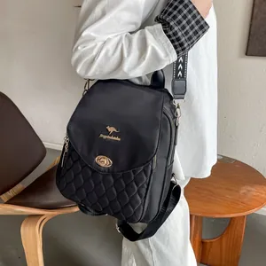 Detail of black quilted backpack with gold twist lock and geometric woven strap on model