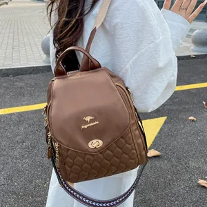 Brown nylon backpack with quilted pattern and gold logo detail shown on a model