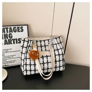 Detail of black and white plaid tweed tote bag with metal chain and monster plush charm