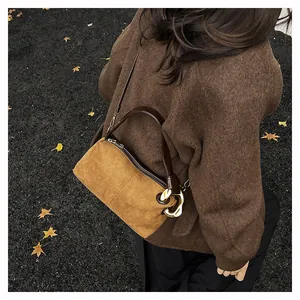 Detail of vintage suede baguette bag featuring a large gold buckle and dark leather strap